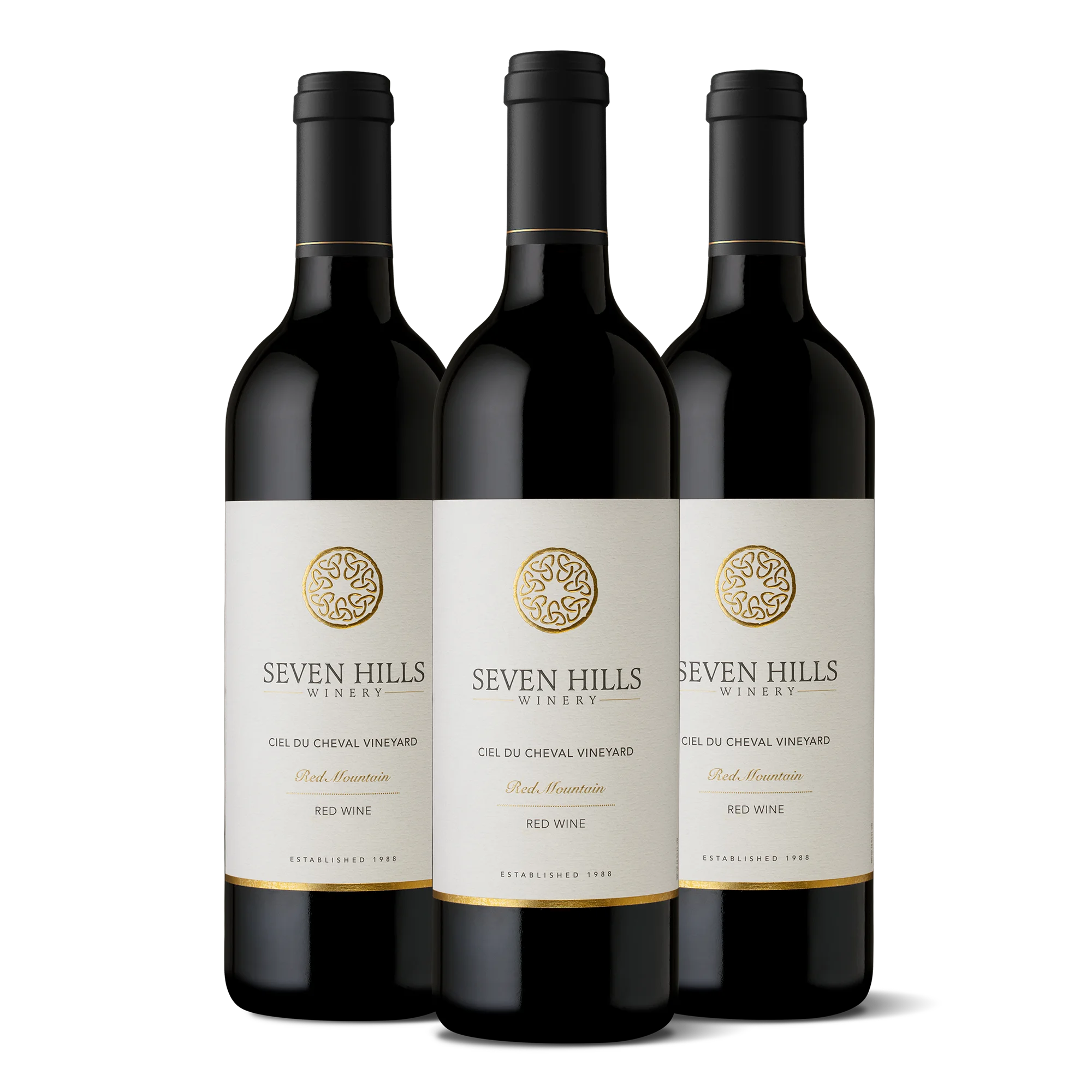Three bottles of Seven Hills Winery red wine from the 2022 Ciel du Cheval 3-Bottle Collection are standing upright in a row on a white background. Each label displays the winery’s gold logo, name, and wine details in elegant black and gold text.