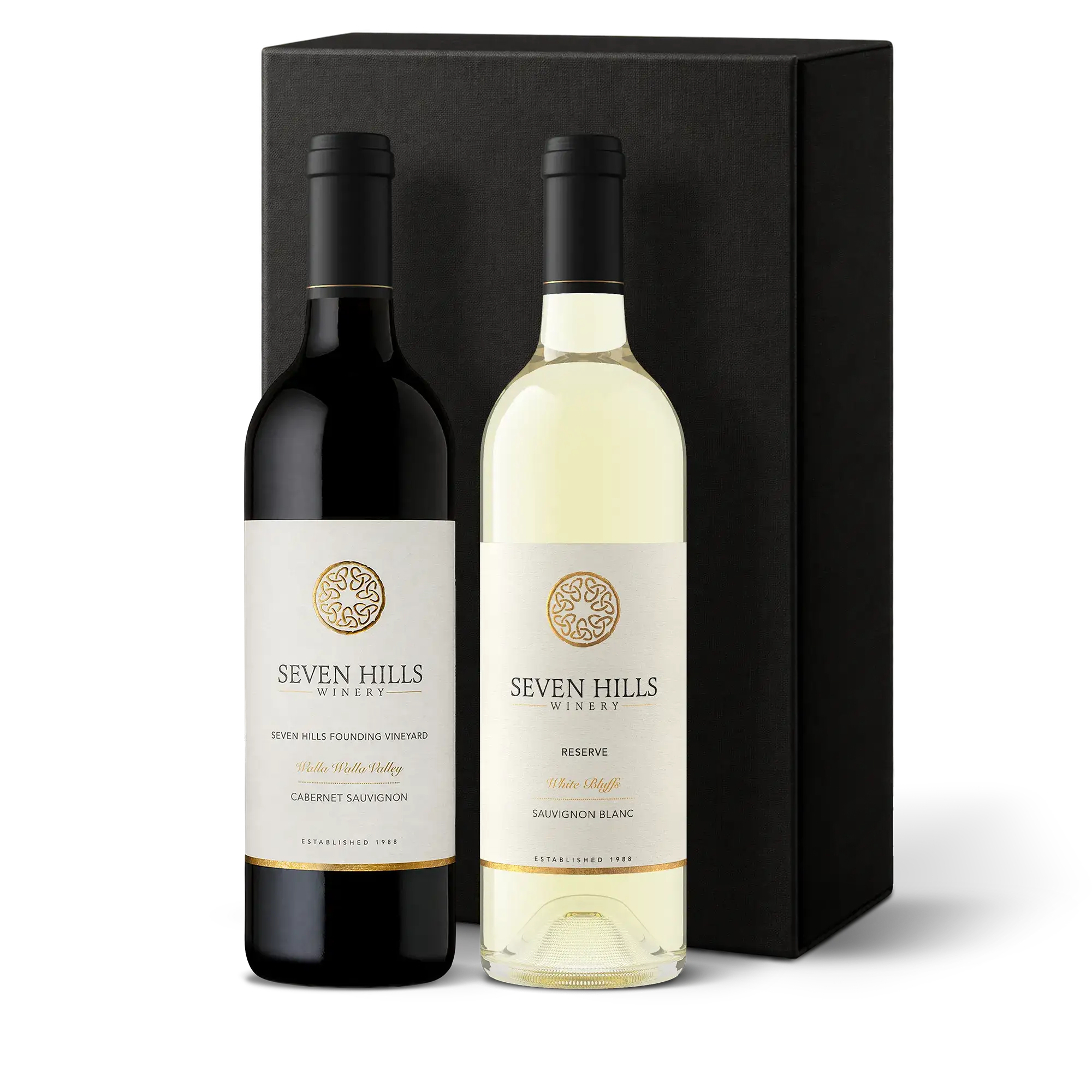 Two bottles of Seven Hills Winery, showcasing Washington’s Finest Wine, stand in front of a tall black gift box—one red and one white—both featuring elegant white labels with gold accents and winery branding. This wine gift is perfect for celebrating special occasions or sharing with someone who appreciates exceptional craftsmanship.